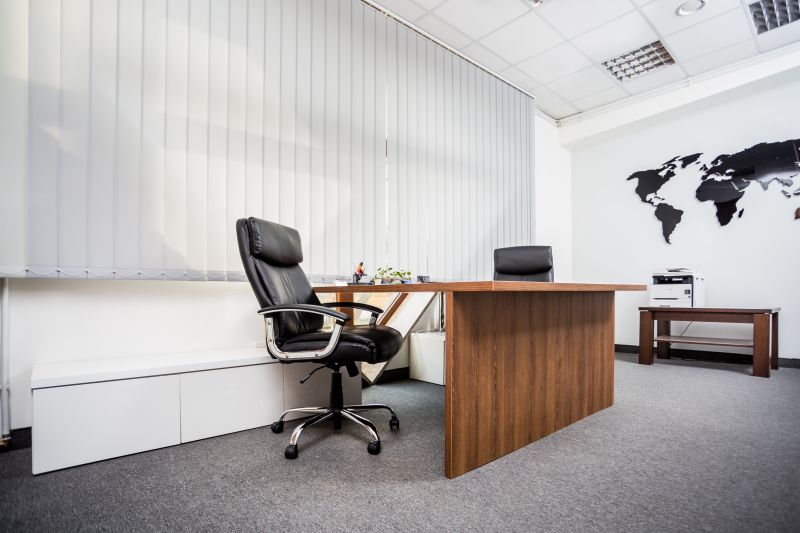 Biuro z drewnianym biurkiem, krzesłem i mapą świata na ścianie. Okno z żaluzjami, drukarka i stolik w tle.