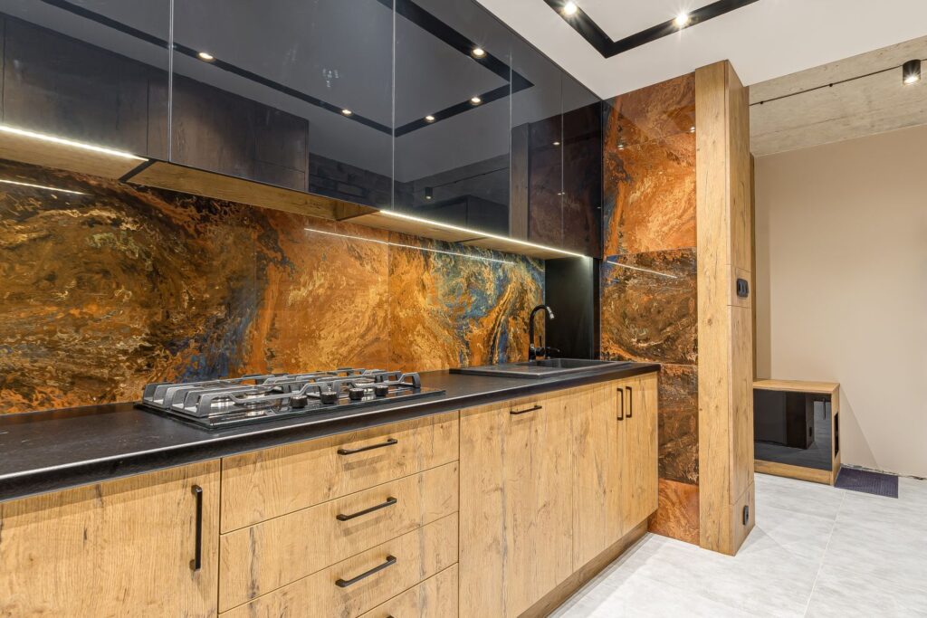 Drewniana kuchnia z marmurową ścianą, czarnym blatem i nowoczesnymi urządzeniami.