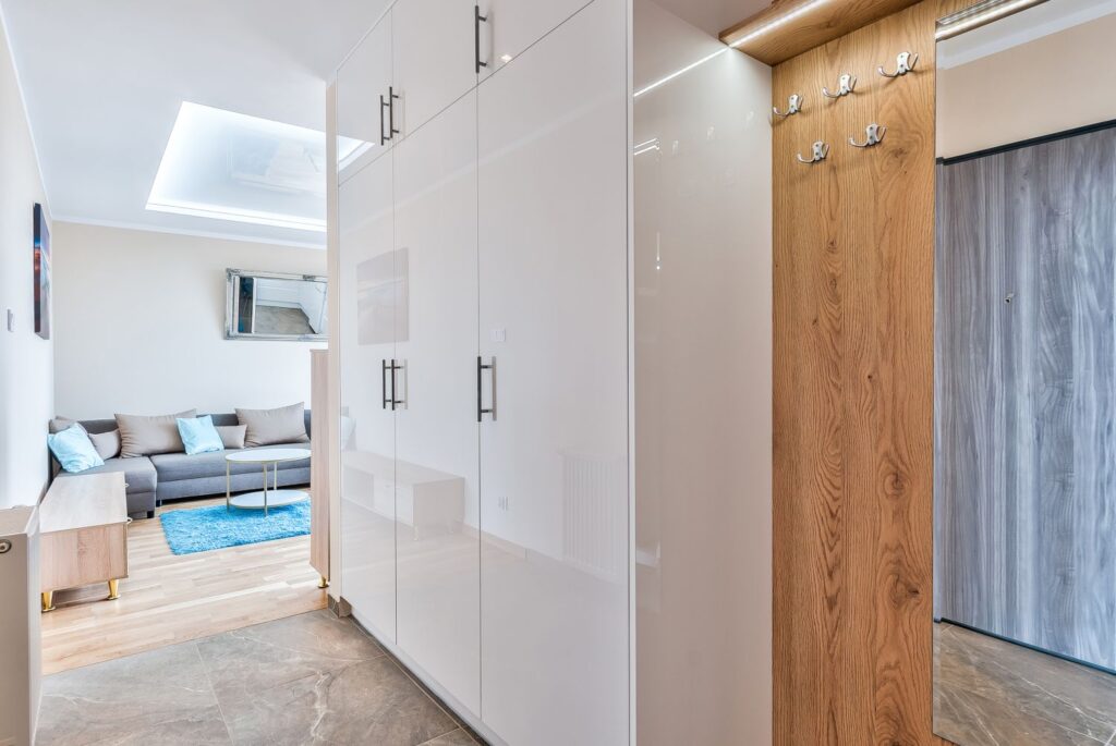 Nowoczesne wnętrze z sofą, niebieskim dywanem i białymi szafkami w korytarzu. Jasne i przestronne pomieszczenie.