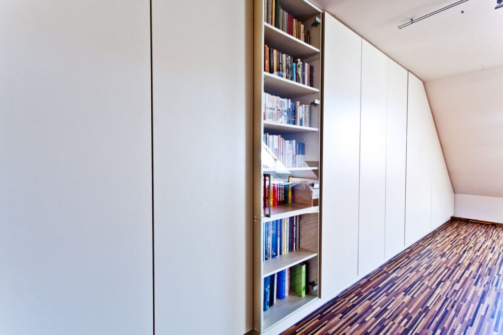 Szafa z ukrytą biblioteczką pełną książek w nowoczesnym wnętrzu z drewnianą podłogą.