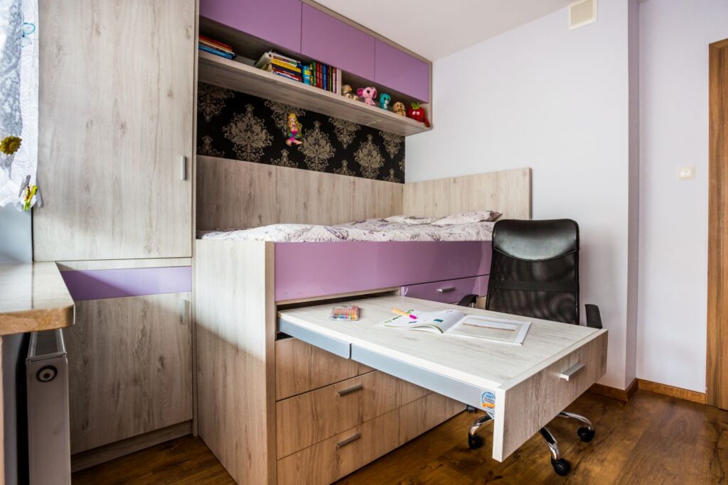 Pokój z nowoczesnym łóżkiem piętrowym, biurkiem i regałem na książki. Stonowane kolory i praktyczne rozwiązanie.